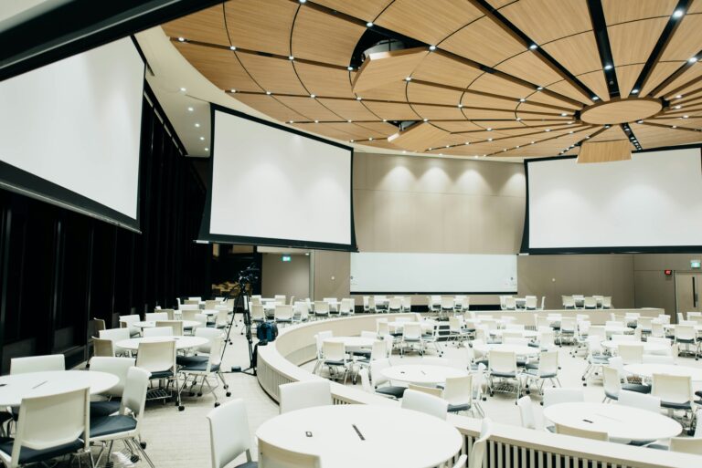 Salle de conférence avec tables rondes et écrans – espace modulable pour congrès et séminaires