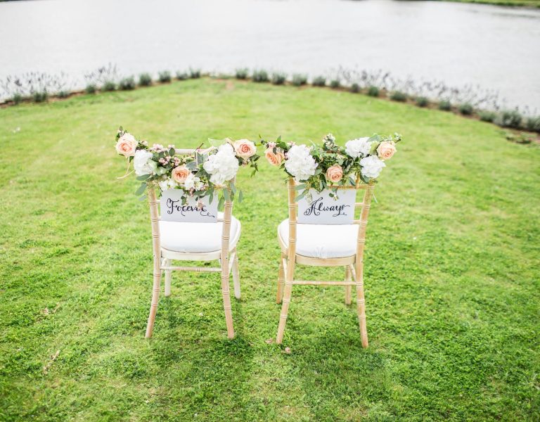 Chaises de cérémonie de mariage en plein air décorées de fleurs blanches et pêche, avec panneaux 'Forever' et 'Always' – décoration romantique au bord de l’eau à Genève