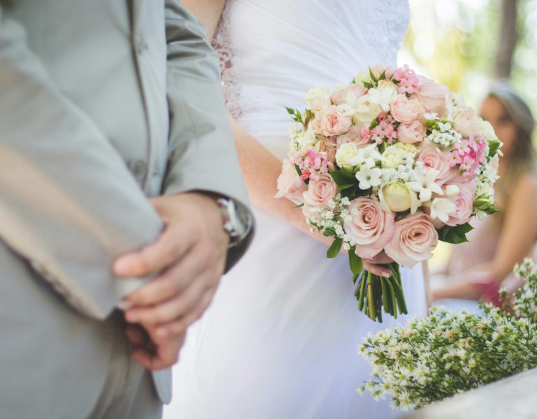 Couple de mariés lors d’une cérémonie en plein air, la mariée tenant un bouquet de roses blanches et roses – organisation de mariage élégante à Genève
